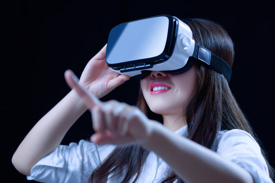 Asian Chinese young woman using vitual reality smart glasses in vitual space.low key photo