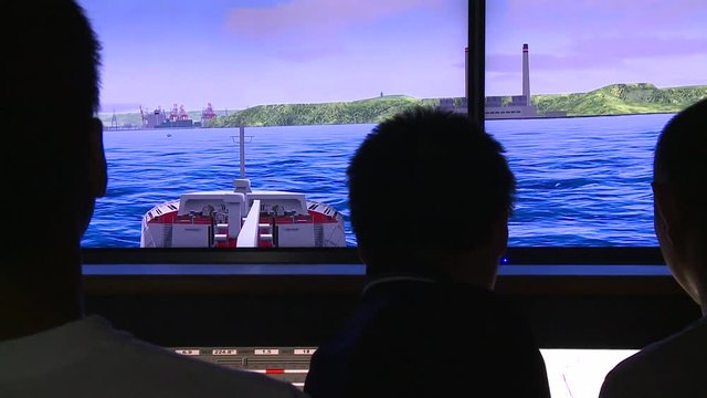 Navigation school. People are practicing on the ship maneuvering simulator in Port. The simulators are used to train workers.