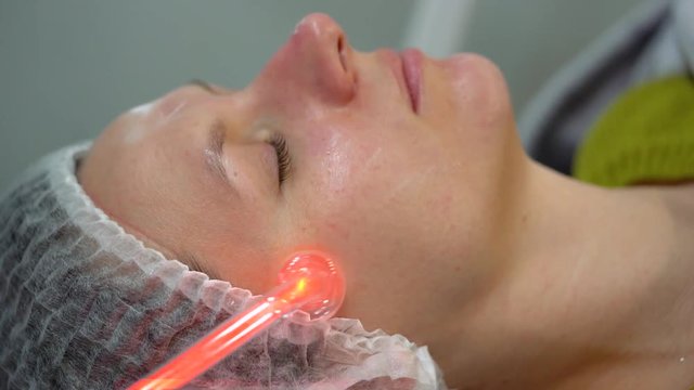 Receiving electric darsonval facial massage procedure