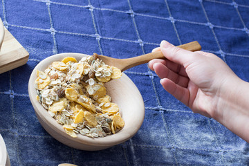 Female hand picking up cereals with wooden spoon