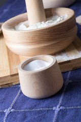 Salt in a small wooden bowl placed on the wooden plate