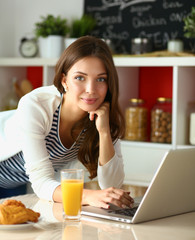 Young woman sitting near desk in the kitchen