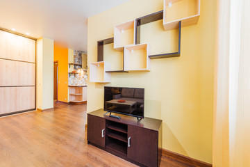 The interior of the living room in orange tones with TV