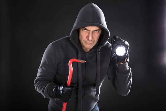 Portrait Of A Male Thief On Black Background