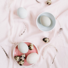 Obraz na płótnie Canvas White Easter eggs, quail eggs and feathers on pink textile background. Flat lay, top view. Traditional spring concept. Easter concept.