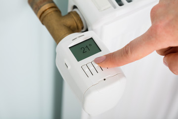 Person Adjusting Temperature On Thermostat