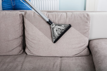 Woman Cleaning Sofa With Vacuum Cleaner
