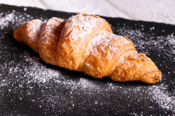 Fresh croissant on a black slate background