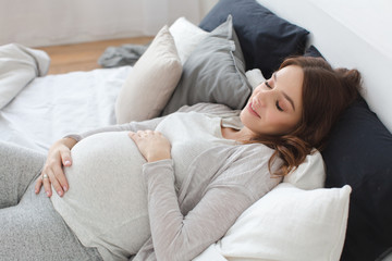 Obraz na płótnie Canvas Pregnant smiling female lying on bed