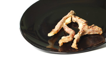 The pork chops bone food leftover on the black color plate represent the food and eating  concept related idea.