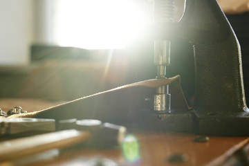 Fototapeta premium Female tailor working on vintage tools pressing buttons onto leather