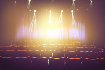 vintage theater with lighting spot on stage before showtime , empty auditorium with seats