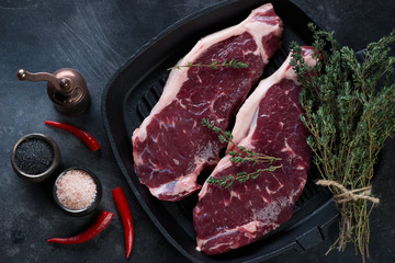 Top view of raw fresh grass-fed striploin beef steaks with condiments