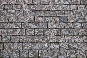 The texture of the stones and rubble on a street pavement.
