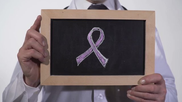 Breast cancer awareness pink ribbon symbol drawn on blackboard in doctor hands