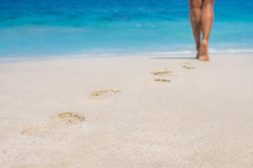 woman legs out of focus, walking on the beach, blurred background