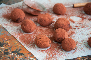 Dark chocolate truffles covered with cocoa powder on a rusty background. Overhead view, 