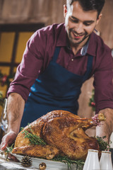 Man putting turkey on festive table