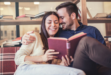 Young couple having a date in cafeteria, surrounded with books on the wooden shelves. Education, dating, relationships, lifestyle