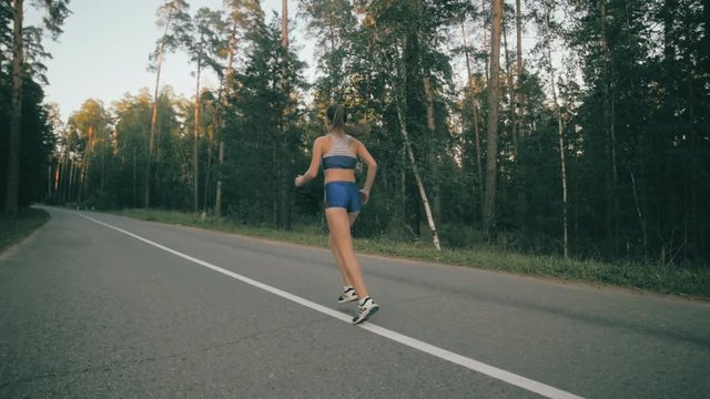 Young woman jogging on a road in city park, forest. Healthy lifestyle concept. HD.