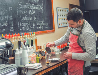 Barista pours coffee into the cup for the cappuccino at the ba