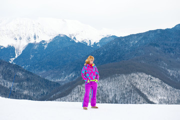 Active sport young girl posing in winter mountains wearing colorful ski suit