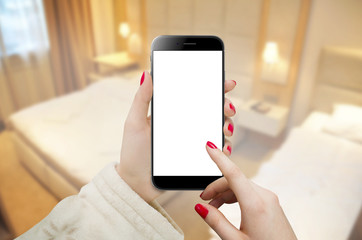 Women in hotel room holding phone with blank screen in hand 
