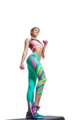Sporty girl engaged in step on platform for step in gym