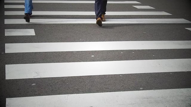 Slow motion footage of people crossing a street on a pedestrian crossing.