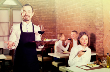 Fototapeta na wymiar positive man waiter demonstrating country restaurant