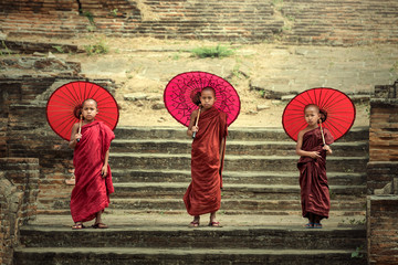 Myanmar The three novice walking on the Mingun pagoda and holding red umbrella in Mandalay,Myanmar.