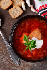Homemade borsch with meat and sour cream on grunge background