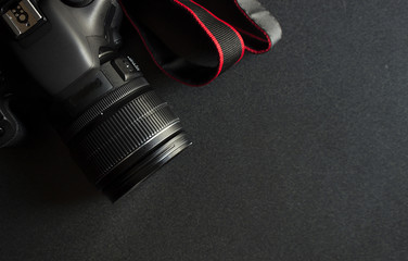 closeup digital camera on black wooden table with soft-focus in the background. dark color tone and over light