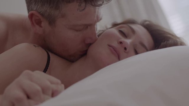 Beautiful passionate couple having sex on bed. Intimate young couple during sensual foreplay in bed.