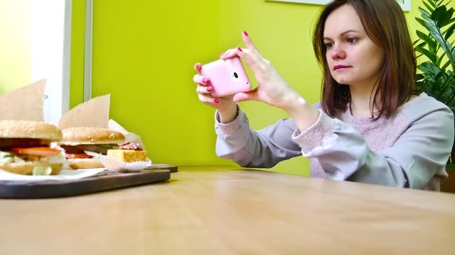 Girl taking photo of food on her cell phone in cafe