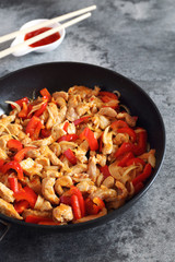 Fried pork with red peppers and hot asian sauce, chopsticks