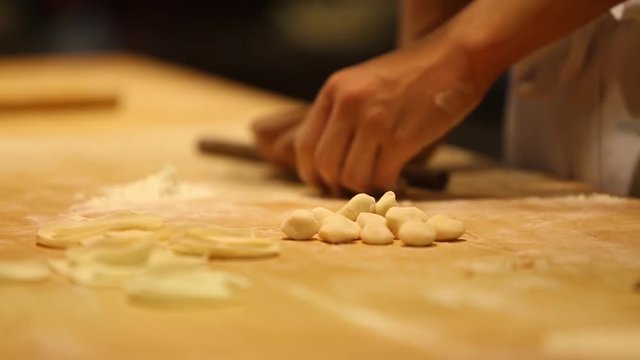 A cook is kneading the dough and shaping it with his hands to make dumplings. The chinese dumpling generally consists of minced meat and finely chopped vegetables wrapped into a piece of dough skin.