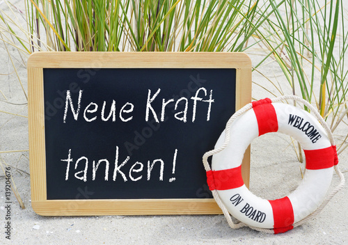 "Neue Kraft tanken Kreidetafel am Strand mit Text und Rettungsring