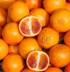 oranges and an orange cut in the stall of greengrocer