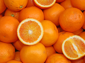 Ripe oranges and an orange cut in the stall of greengrocer