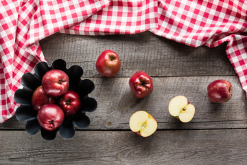Ripe red apples in baking form on wooden board with red checkered napkin.