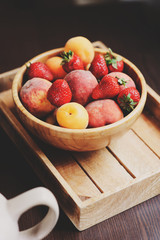 fresh summer fruits on wooden plate. Strawberries, peaches and apricots in rustic farm kitchen