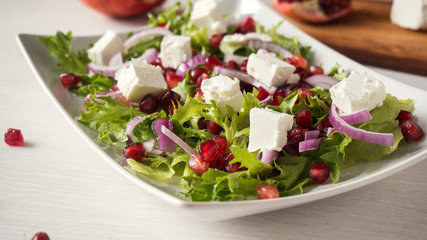 Healthy salad with pomegranate seeds, feta cheese and red onion.