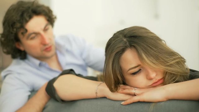 Man comforting his worried girlfriend while sitting on the sofa
