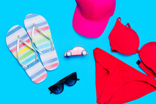 beautiful swimsuit, sunglasses, car shaped toy, cap and sandals on the wonderful blue background