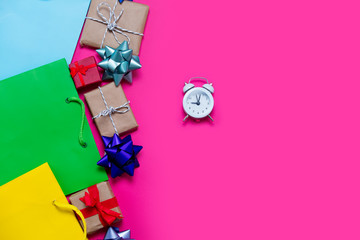 beautiful small gifts, bows, alarm clock and colorful cool shopping bags on the wonderful pink background