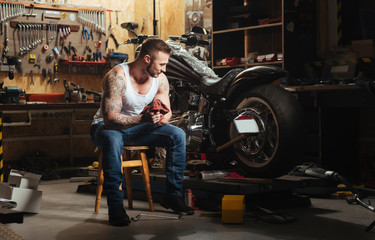 Naklejka na ściany i meble Delighted motorcyclist while repairing his bike