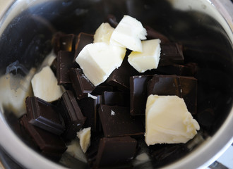Pieces of chocolate and butter melt in a steel bowl. The process of making candy or dessert