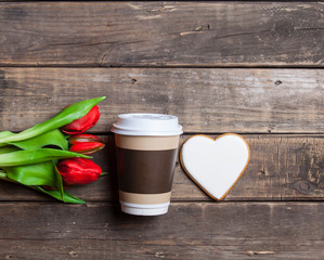 heart shaped cookie, cup of coffee and bunch of tulips lying on the wonderful brown wooden background