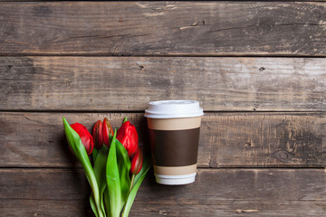 cup of coffee and bunch of tulips lying on the wonderful brown wooden background